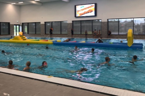 Zwembad met kinderen en een opblaasbare stormbaan erin.